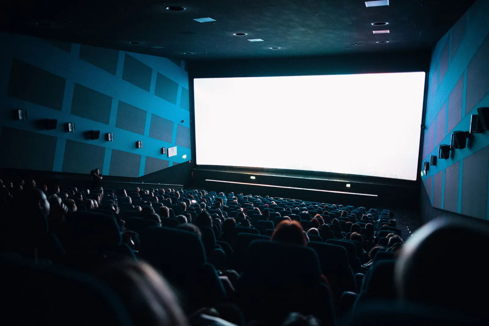 A full cinema auditorium facing a bright screen