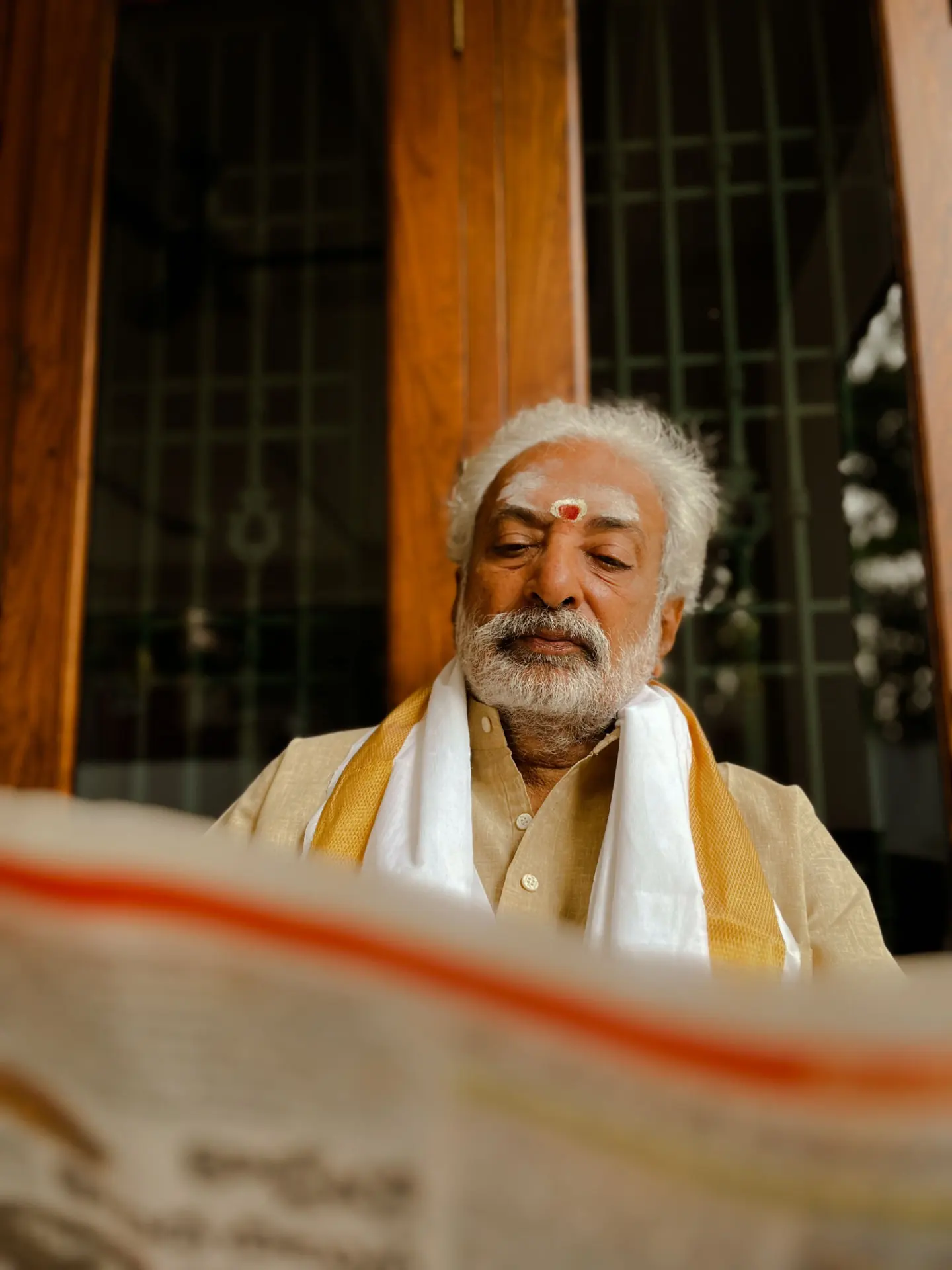 An elderly man reading a regional daily newspaper at his doorstep